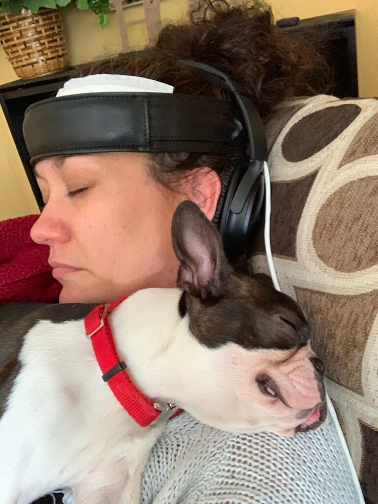 Person wearing a headset device resting with a small dog